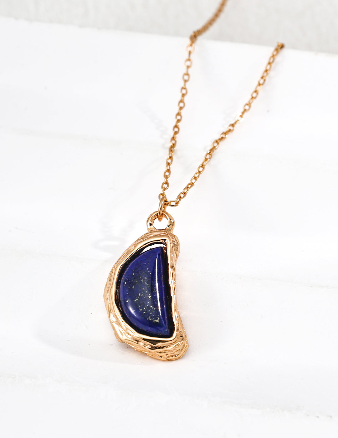 Closed look of vintage gold arc pendant necklace with natural blue lapis lazuli stone and organic textured molten framing