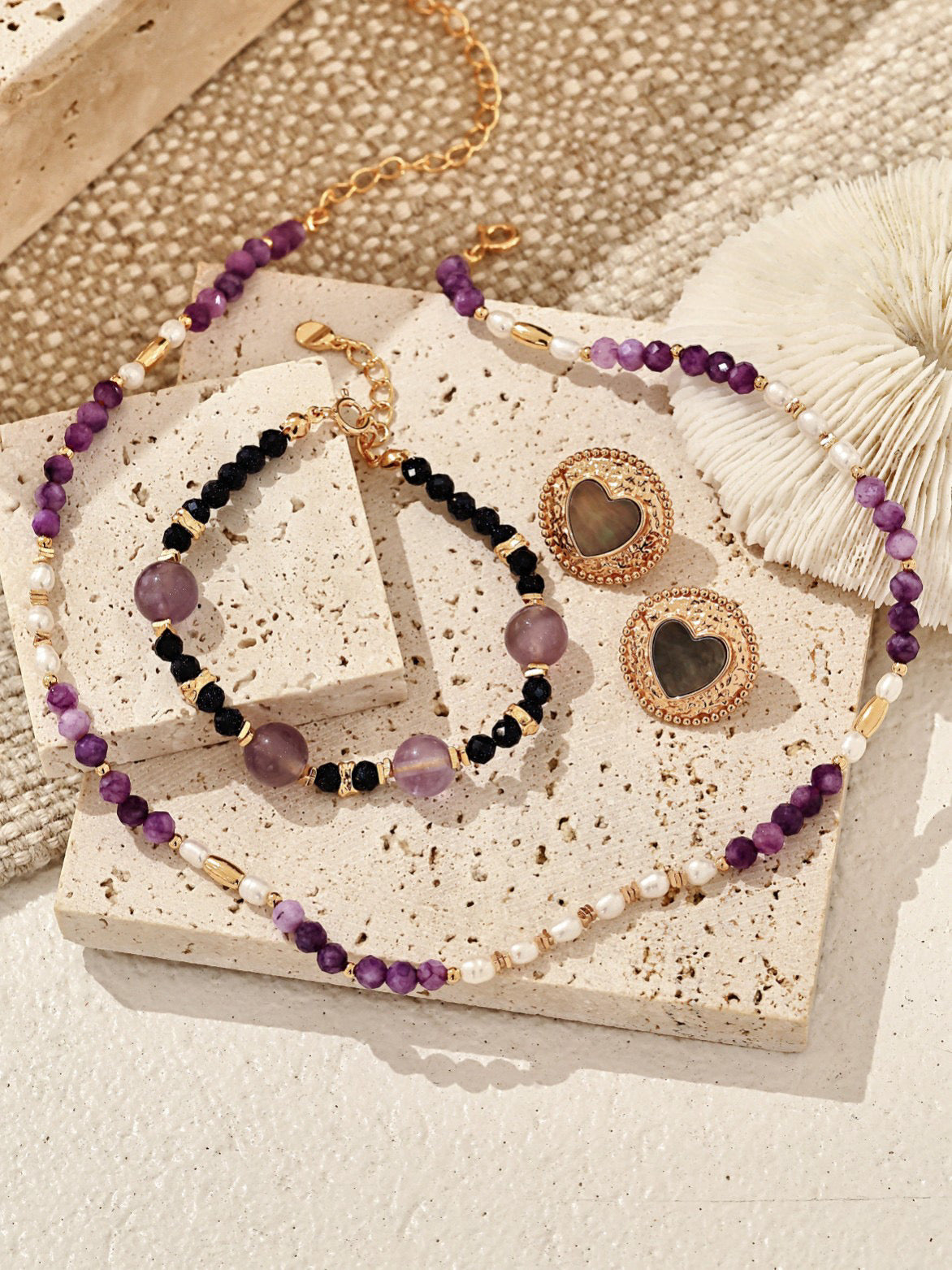 Set of beaded jewelry with heart-shaped charms on a textured surface