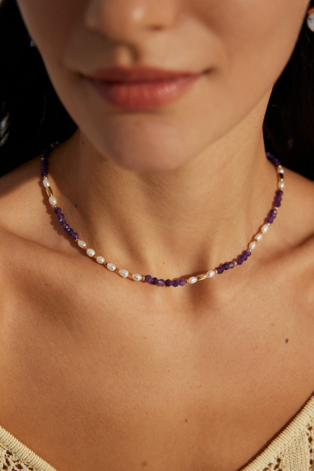 A model wearing an elegant retro choker necklace made of faceted natural purple amethyst beads, smooth white freshwater pearls, and high-polished gold spacers