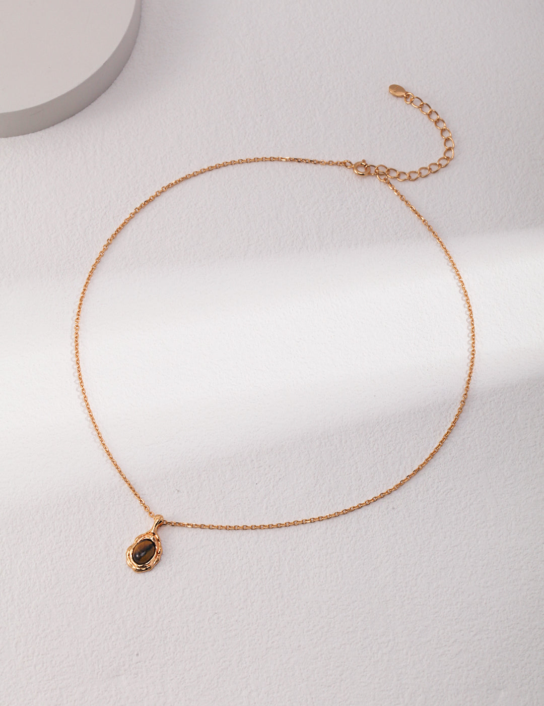 An organic molten gold framed round tiger's eye pendant necklace