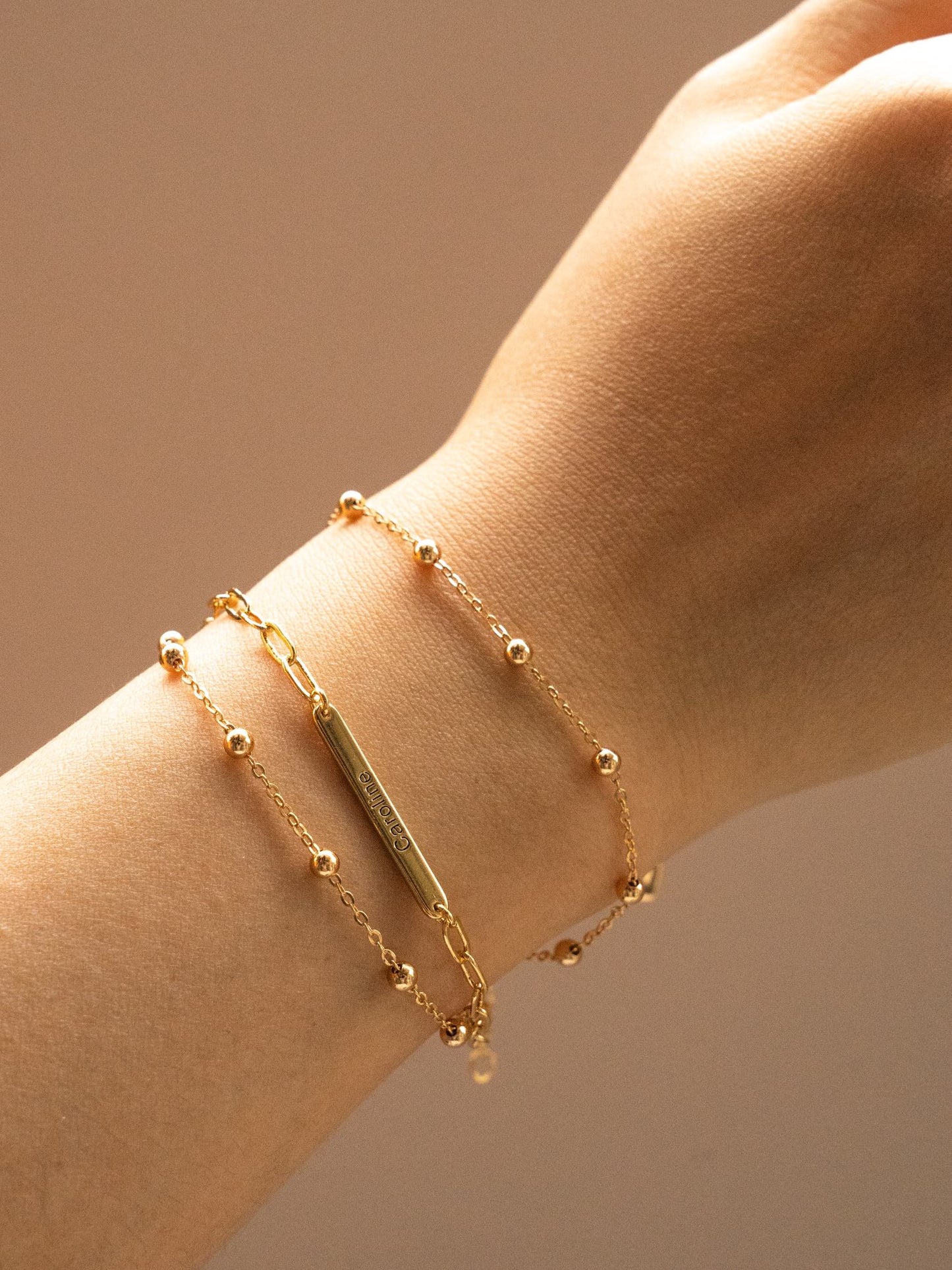 Close-up of a wrist wearing a gold custom name bracelet