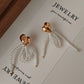 Heart-shaped earrings with pearl bow on a jewelry display card.