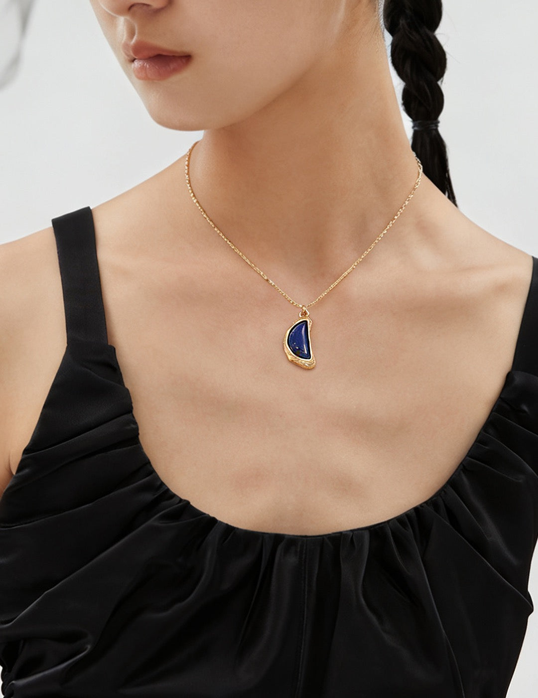 A model wearing vintage gold arc pendant necklace with natural blue lapis lazuli stone and organic textured molten framing