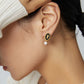 A model wearing vintage gold queen cameo drop earrings with premium black enamel backdrop and dangling natural freshwater pearls