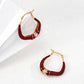 Red hoop earrings with gold accents on a white background