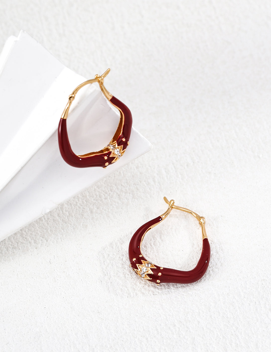 Red hoop earrings with gold accents on a white background