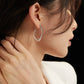 Close-up of a person wearing a silver hoop earring with a blurred background
