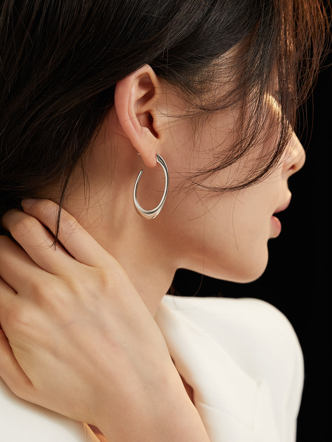Close-up of a person wearing a silver hoop earring with a blurred background