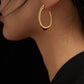 Gold hoop earring worn by a person with a blurred background