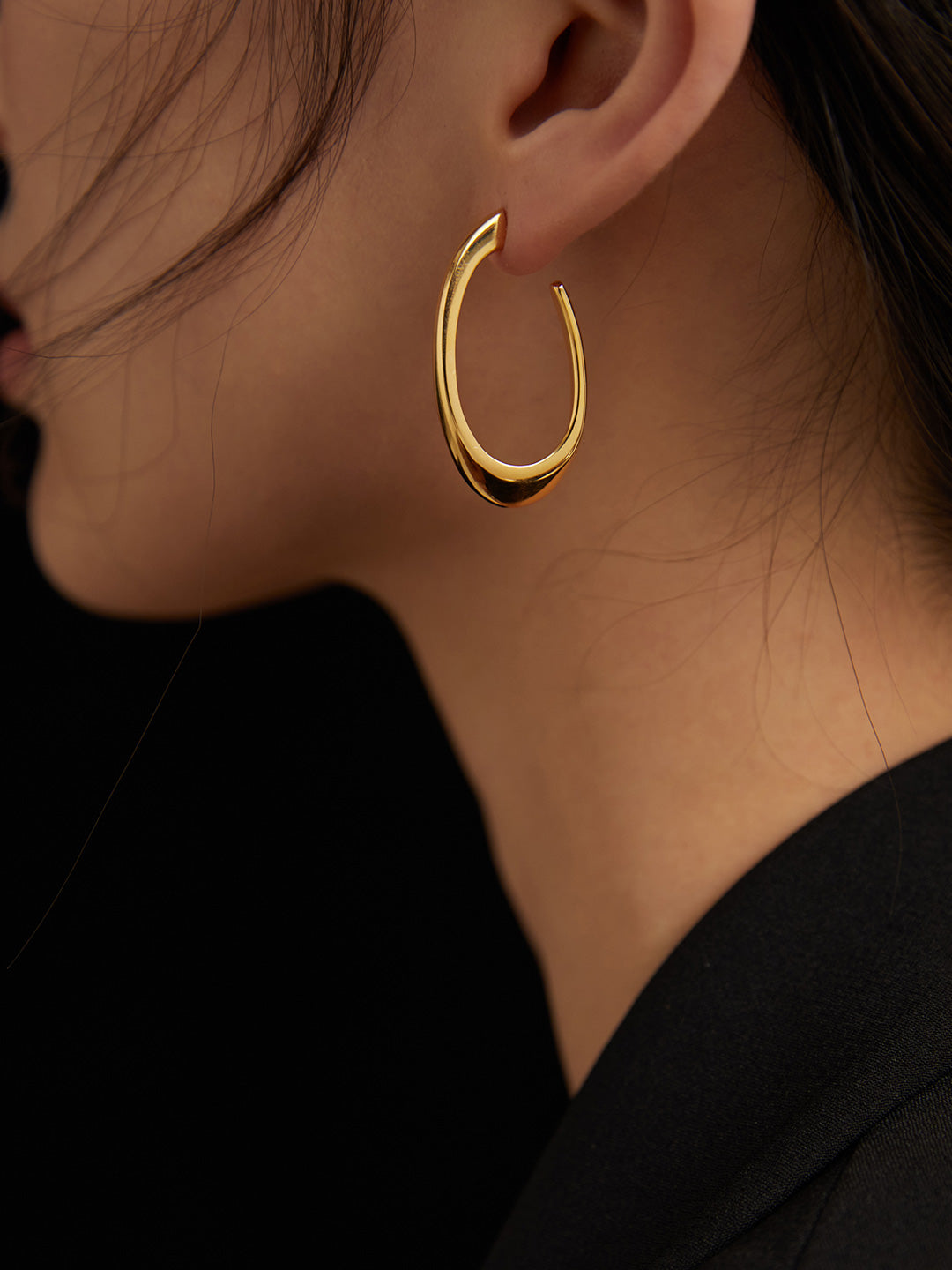 Gold hoop earring worn by a person with a blurred background