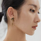 Close-up of a model wearing an ornate gold earring with a dark gemstone.