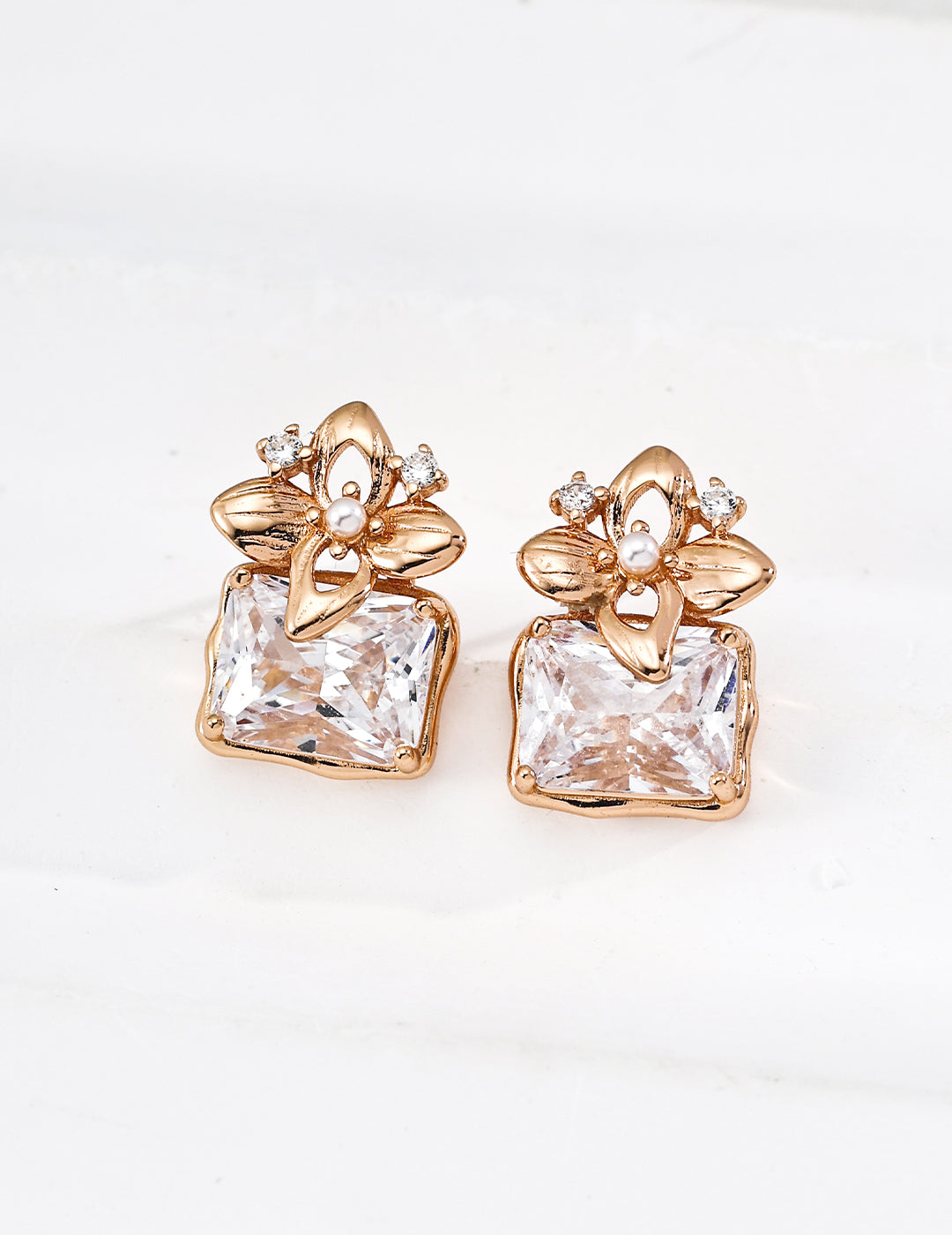 Gold earrings with clear gemstones on a white background