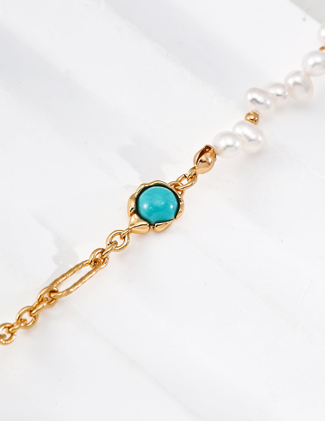 Gold bracelet with a turquoise stone on a white background