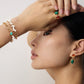 A model wearing green gemstone earrings with a plain background