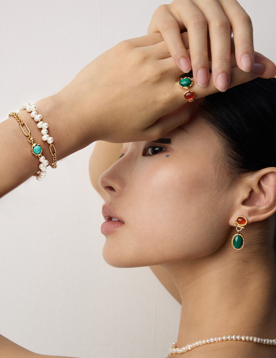 A model wearing green gemstone earrings with a plain background