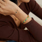 Person wearing a colorful bracelet on a plain background