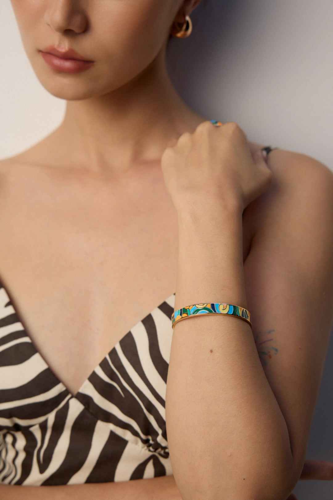 A model wearing vibrant artistic open cuff bangle with multi-color hand-painted enamel abstract oil painting motifs in high polished gold finish