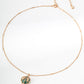 Gold necklace with a green pendant on a white background