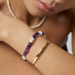 Close-up of a model wearing elegant double-strand bracelet with one layer of natural pearls and one layer of gold chain with purple amethyst gemstones
