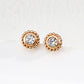 Pair of gold earrings with clear gemstones on a light background