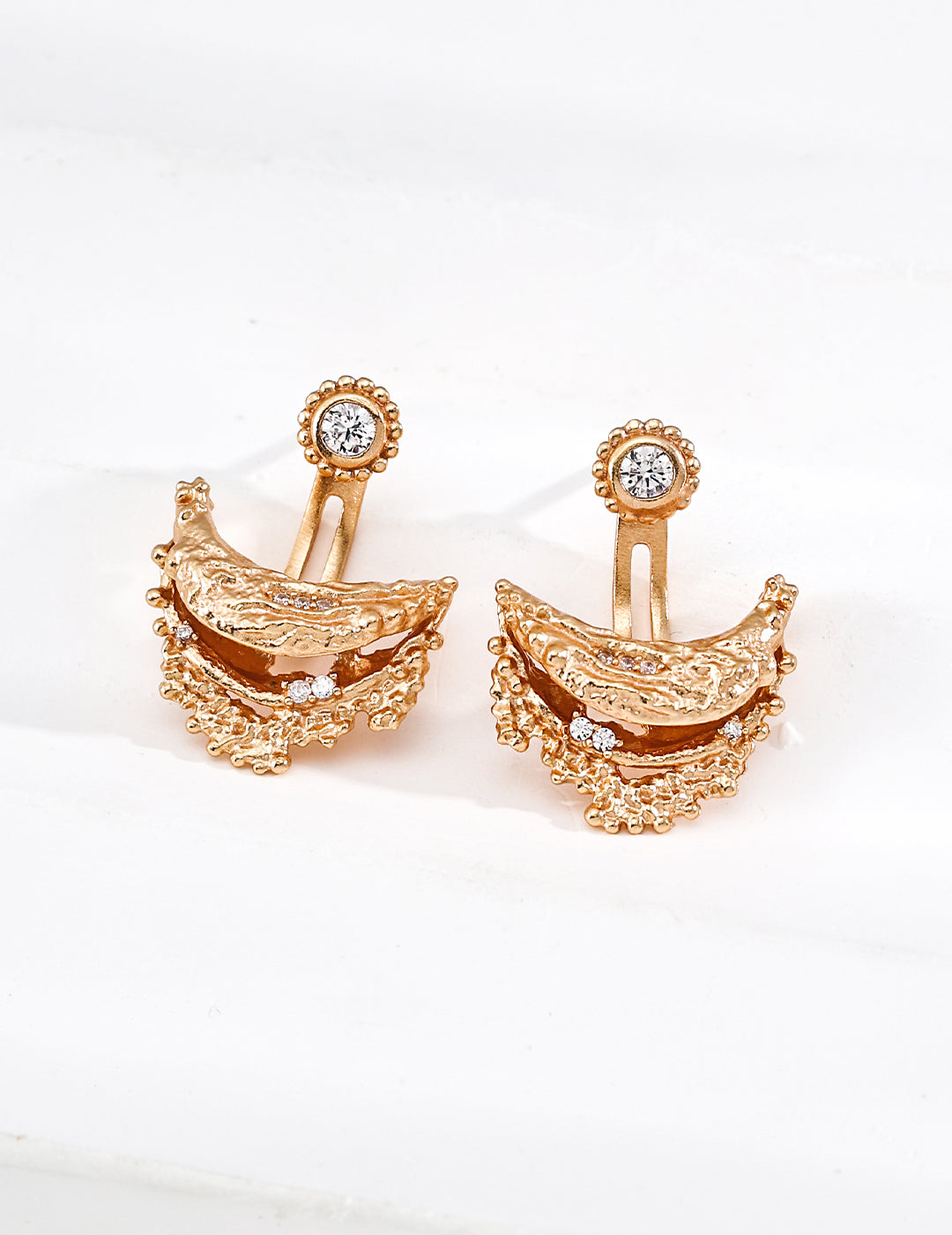 Pair of gold earrings with intricate designs on a white background