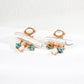 Pair of gold earrings with pearls and blue gemstones on a white background