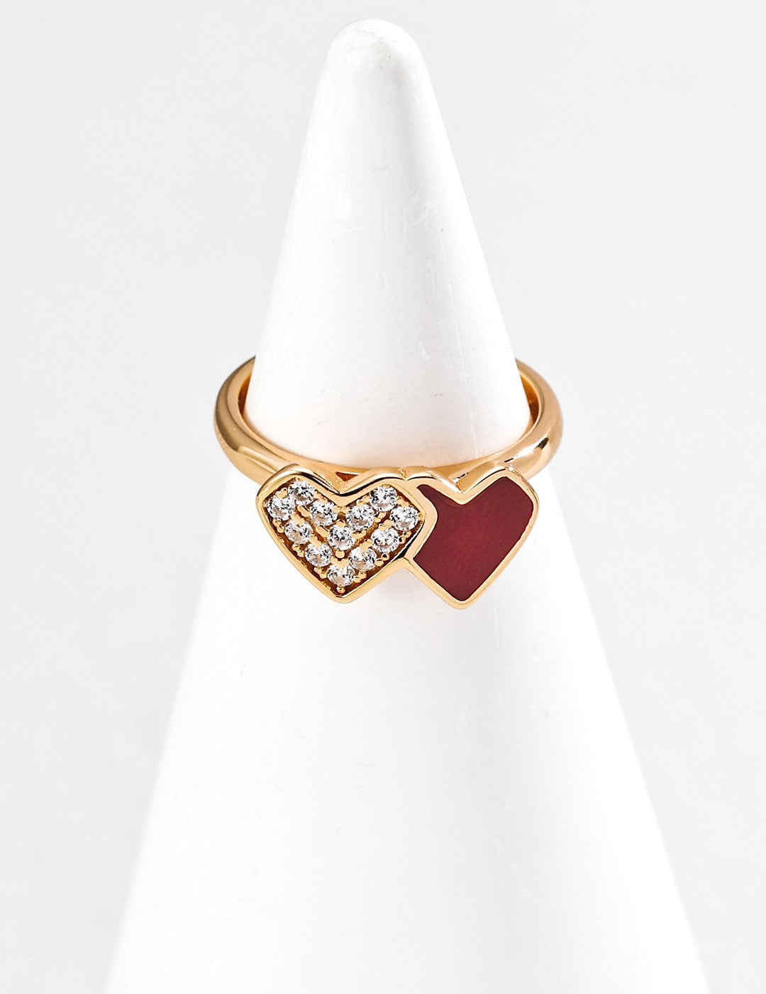 Gold ring with heart design on a white stand