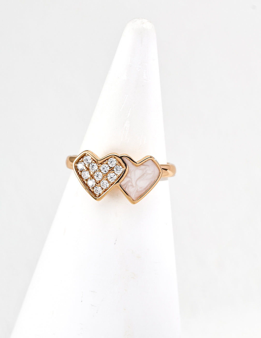 Heart-shaped ring with gold and white stones on a white stand