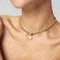 Gold necklace with a pearl pendant on a model against a neutral background