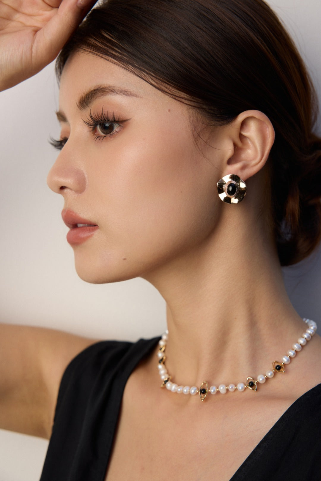 A model wearing regal vintage gold statement earrings featuring large wavy metallic discs centering a polished natural black onyx stone