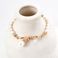 Close-up look of the elegant retro gold bracelet with a central fluid intertwined vine knot holding natural freshwater pearl charms on a lustrous pearl strand