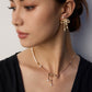 A model wearing a luminous natural freshwater pearl stud earrings with a dangling high-polished fluid gold metallic ribbon bow knot pendant