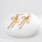 Dare To Sparkle - Luminous natural freshwater pearl stud earrings with a dangling high-polished fluid gold metallic ribbon bow knot pendant