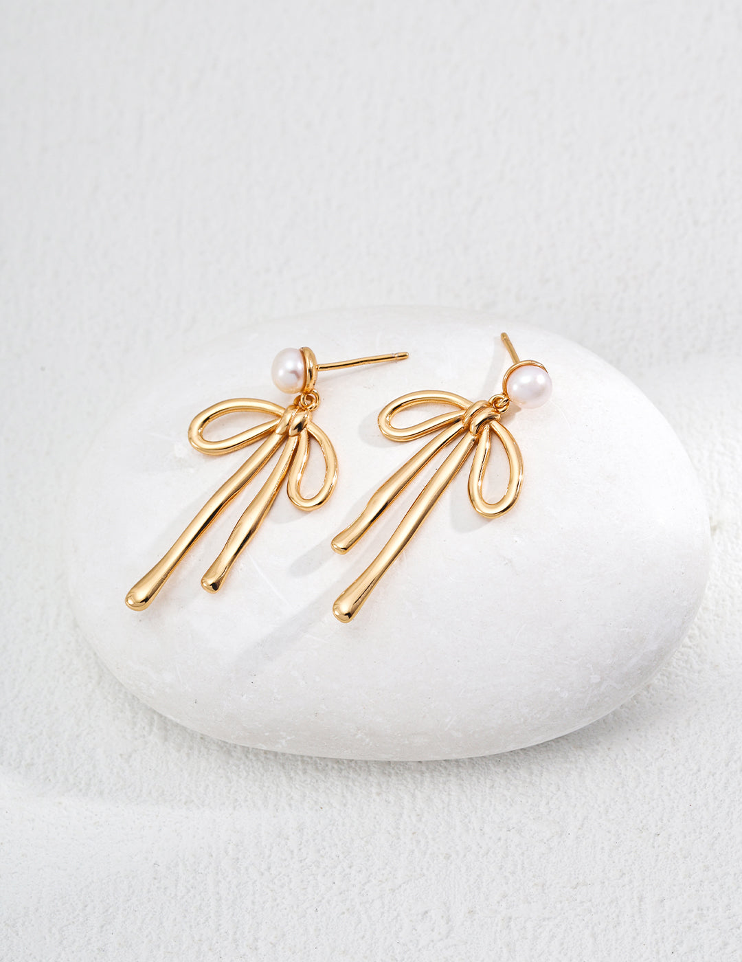 Dare To Sparkle - Luminous natural freshwater pearl stud earrings with a dangling high-polished fluid gold metallic ribbon bow knot pendant
