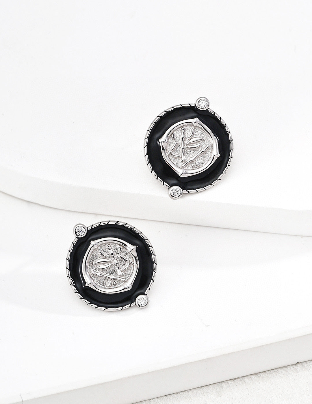 Chinoiserie chic round stud earrings with black enamel borders centering a metallic bamboo relief plaque with micro cz gems in silver