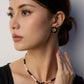 A model wearing a chinoiserie chic round stud earrings with black enamel borders centering a metallic bamboo relief plaque with micro cz gems in gold