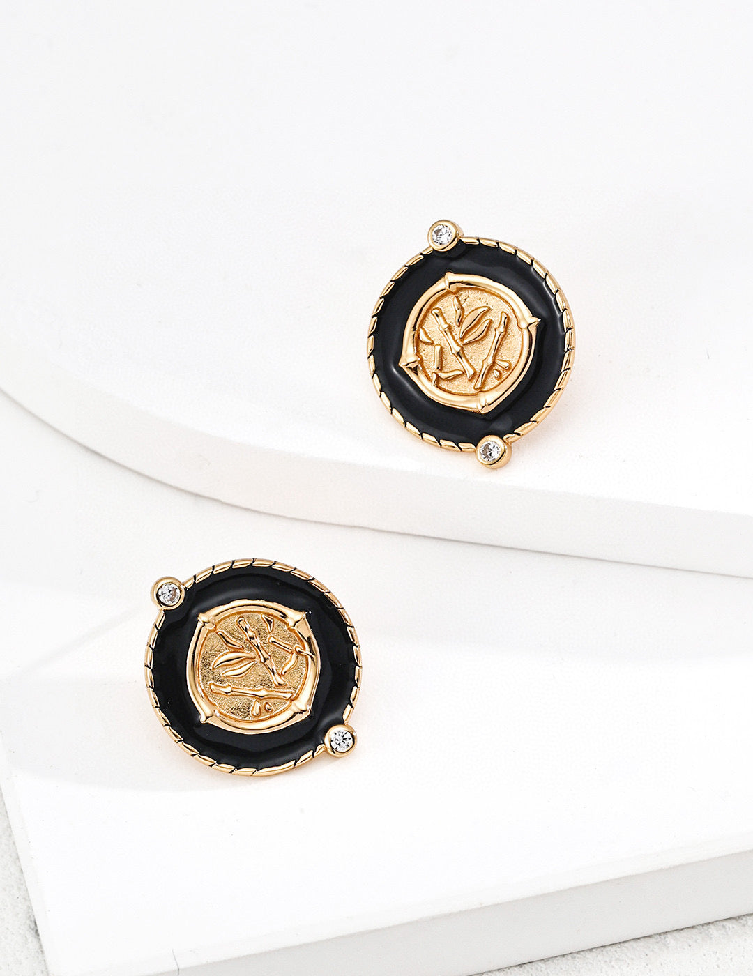 Chinoiserie chic round stud earrings with black enamel borders centering a metallic bamboo relief plaque with micro cz gems in gold