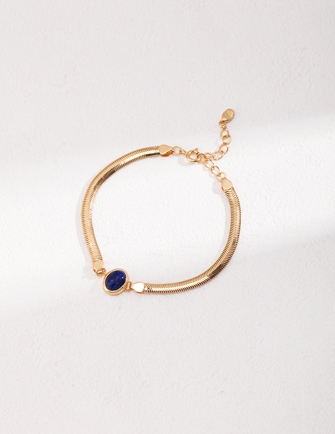 Dare To Sparkle - Sleek 18k gold plated flat herringbone snake chain bracelets with a central bezel-set oval natural lapis lazuli