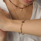 A model wearing a sleek 18k gold plated flat herringbone snake chain bracelets with a central bezel-set oval natural tiger's eye stone
