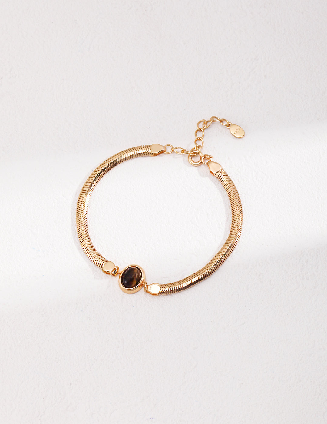 Dare To Sparkle - Sleek 18k gold plated flat herringbone snake chain bracelets with a central bezel-set oval natural tiger's eye stone