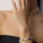 Close-up of a model wearing a luminous natural freshwater pearl strand bracelet with dark blue lapis lazuli accents and a central gold celestial crescent moon charm with a cz crystal