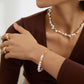 Close-up of a person wearing gold jewelry with pearls on a neutral background