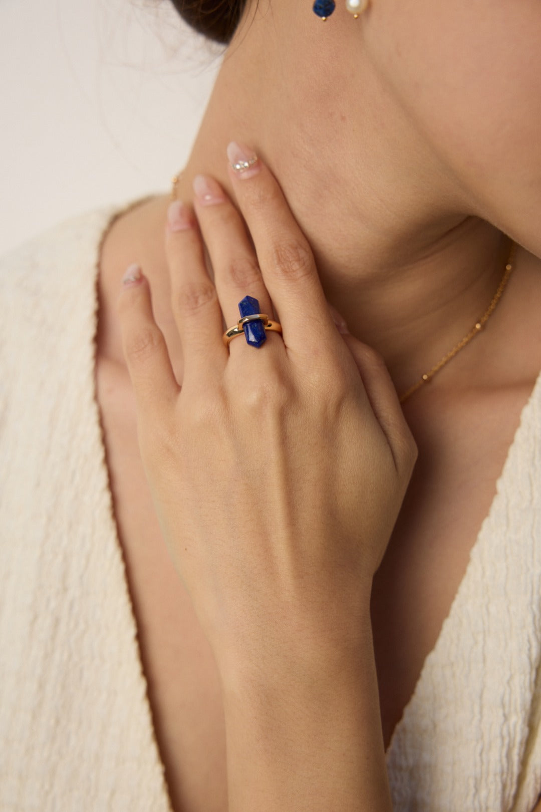 A model wearing an antique-inspired statement open adjustable ring featuring a central round natural deep blue lapis lazuli stone within a geometric gold bezel