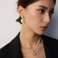 Woman wearing a necklace and earrings against a neutral background
