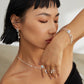 Woman wearing a necklace, ring, and bracelet with a blurred background