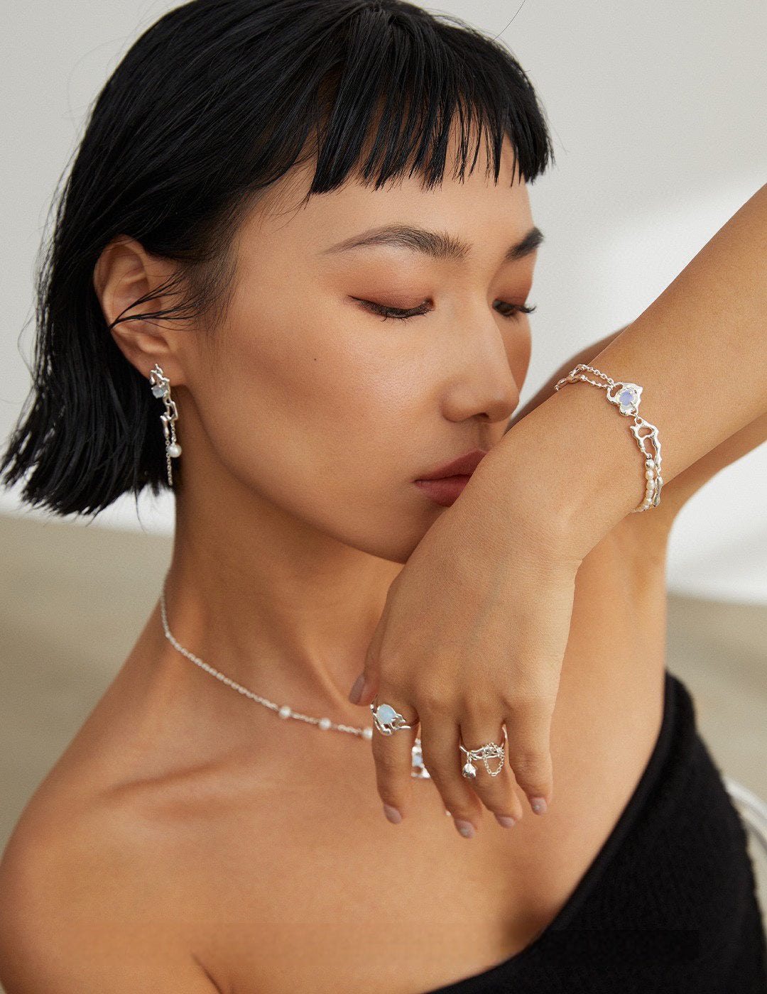 Woman wearing a necklace, ring, and bracelet with a blurred background