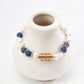 Bracelet with blue beads and gold accents on a white vase