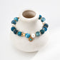 Blue beaded bracelet with gold accents on a white vase against a white background