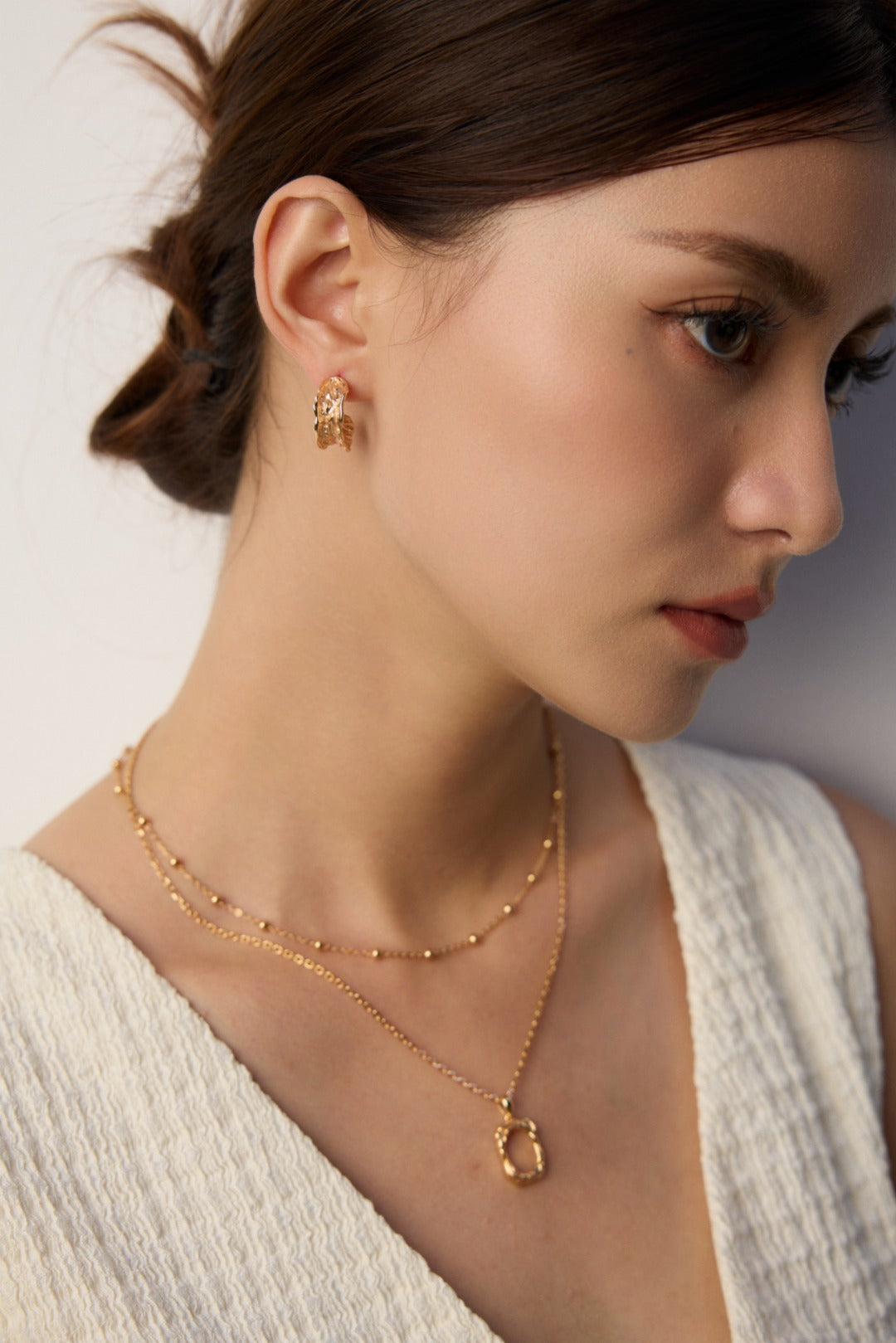A model wearing a versatile high-polished sterling silver faceted bead chains shown with and without a detachable starburst engraved round coin pendant in gold