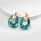 Teal hoop earrings with gold accents on a white background